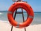 Orange lifebuoy on a special stand against the backdrop of the bay of the sea and the distant shore.