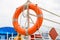 The orange lifebuoy is tied to a fence on the river pier. side and bottom view.
