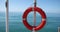 Orange lifebuoy weights on mast against the backdrop of sea