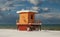 An orange lifeguard tower on a snowy beach