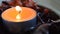 Orange light candle with potpourri with the flame waving in the wind inside a wood bowl.