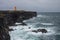 Orange lighthouse on the black rock cliff of western Icelandic