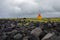 Orange lighthouse on the black rock cliff of western Icelandic