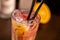 Orange long drink with grenadine and ice on wooden table