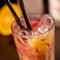 Orange long drink with grenadine and ice on wooden table