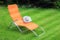 Orange lounge sunbed standing on green grass