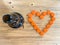 An orange love heart made from beer bottle tops lids and a brown glass beer bottle on a rustic wooden table. Beer drinkers and