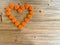 An orange love heart made from beer bottle tops lids on a rustic wooden table. Beer drinkers Valentine`s day concept top view wit