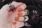 Orange matte nails on black blurry star background. Halloween nail art