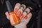 Orange matte nails on black blurry star background. Halloween nail art