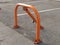 Orange mechanical parking barrier with a lock on the gray aswhite stripephalt