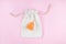 Orange menstrual cup on cotton bag on pink background.