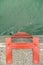 Orange metal safety ladder on concrete breakwater