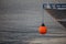 Orange mooring buoy and a ship