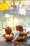 An orange mug in a scarf with hot tea, pumpkins, yellow dry maple leaves, a book on the windowsill, raindrops on the window -