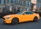 Orange muscle car Ford Mustang at the countryside. Front headlights of yellow modern car on a street