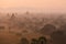 Orange mystical sunrise landscape view with silhouettes of old ancient temples and palm trees in dawn fog from balloon