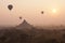 Orange mystical sunrise landscape view with silhouettes of old ancient temples and palm trees in dawn fog from balloon