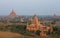 Orange mystical sunrise landscape view with silhouettes of old ancient temples and palm trees in dawn fog from balloon