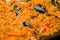 Orange paella with shrimp, mussel, rice, spice, saffron in huge paella pan
