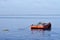 Orange painted metal barge anchored along ocean bay