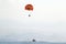 Orange paraglider with a cheerful pattern hanging over a boat