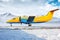 Orange passenger turboprop aircraft on the winter airport apron on the background of high scenic mountains