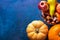 Orange and peachy pumpkins ripe organic red glossy apples pomegranates chestnuts pears persimmon in basket on dark blue background