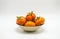 Orange persimmons in a small bowl on white