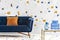 Orange pillow on blue couch in colorful living room interior with table and wallpaper. Real photo