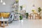 Orange pillows on grey settee in spacious flat interior with chairs at wooden table. Real photo