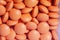 Orange pills piling in a glass containter, close-up.