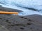 Orange pipe with water poured into sea, beach pollution. Tourist industry impact on natural seaside. Construction pipe