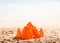 Orange plastic castle in sand on seashore.