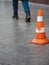 Orange plastic safety cone with strips of retro reflective film on the sidewalk paved with granite tiles in Moscow, Russia.
