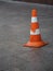 Orange plastic safety cone with strips of retro reflective film on the sidewalk paved with granite tiles in Moscow, Russia