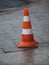 Orange plastic safety cone with strips of retro reflective film on the sidewalk paved with granite tiles in Moscow, Russia