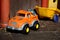 Orange plastic toy car with blue rubber ball in closeup view. outdoor concept