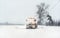 Orange plow truck on snow covered road, gray sky and trees in background -  winter road maintenance