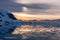 Orange polar sunset over the mountains with glaciers and drifting melted icebergs at Lemaire Strait, Antarctica