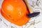 Orange protective hard hat with claw hammer on light gray cement. Home repairing and improvement, house building concept.