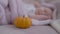 Orange pumpkin on bed with blurred sleeping infant at background. Close-up Halloween vegetable indoors with carefree