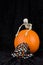 Orange pumpkin on black velvet background, fabric pumpkin pattern face mask, plastic skeleton, celebrating Halloween