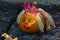Orange pumpkin decorated as princess with painted eyes and mouth, crown flom fluffy pink wire and hair from wooly strings