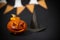 an orange pumpkin with facial features carved next to a black pointed hat and a Halloween garland in the background