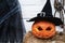 Orange pumpkin for halloween in black witch, wizard hat, jack-o-lantern with scary carved eyes, mouth. Hay, haystack near barn.