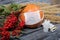 Orange pumpkin in a medical mask. Lies on black pine boards. Nearby is a bouquet of dried grass and mountain ash. There is a