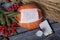 Orange pumpkin in a medical mask. Lies on black pine boards. Nearby is a bouquet of dried grass and mountain ash. There is a