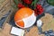 Orange pumpkin in a medical mask. Lies on black pine boards. Nearby is a bouquet of dried grass and mountain ash. There is a