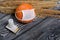 Orange pumpkin in a medical mask. Lies on black pine boards. Nearby there is a candle stub and a bouquet of dried grass